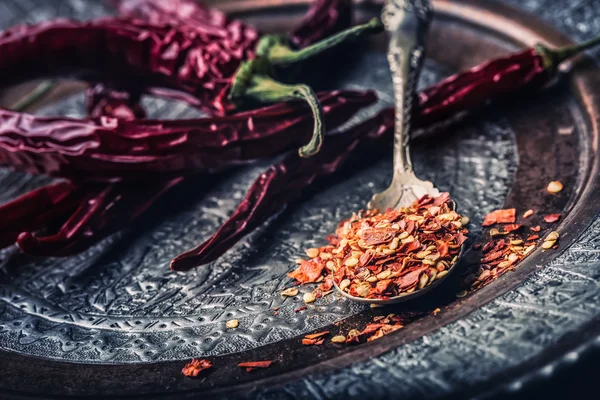 Chili. Chili peppers. Several dried chilli peppers and crushed peppers on an old spoon spilled around. Mexican ingredients - cuisine