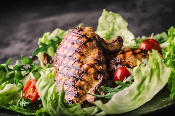 Grilled chicken breast in different variations with lettuce salad cherry tomatoes  mushrooms herbs cut lemon on a wooden board or teflon pan. Traditional cuisine. Grill kitchen