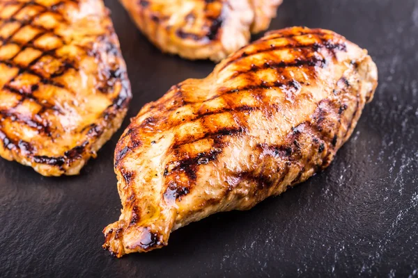 Grilled chicken breast in different variations with cherry tomatoes,  mushrooms, herbs, cut lemon on a wooden board or teflon pan. Traditional cuisine. Grill kitchen