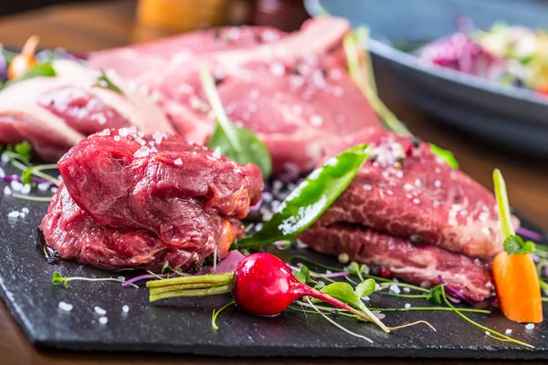 Steak.Beef steak.Meat.Portioned meat.Raw fresh meat.Sirloin steak.T-Bone steak. Flank steak. Duck breast. Vegetable decoration. Portioned meat prepared for processing in a restaurant or hotel kitchen