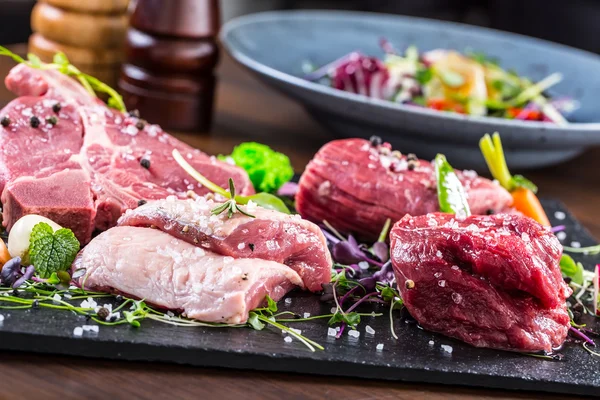 Steak.Beef steak.Meat.Portioned meat.Raw fresh meat.Sirloin steak.T-Bone steak. Flank steak. Duck breast. Vegetable decoration. Portioned meat prepared for processing in a restaurant or hotel kitchen