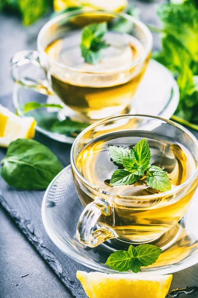 Tea. Mint Tea. Herbal tea. Mint leaf. Mint leaves. Tea in a glass cup, mint leaves, dried tea, sliced lime. herbs tea and mint leaves on a slate plate in a restaurant or teahouse tea room