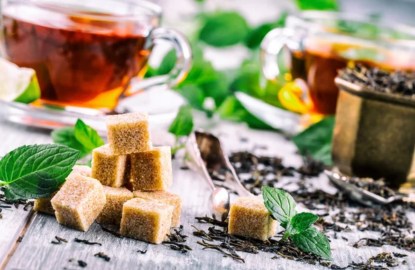 Sugar. Cane sugar. Cane sugar cubes heap close up macro shot. Tea in a glass cup, mint leaves, dried tea, sliced lime, cane brown sugar