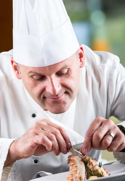 Chef. Chef cooking.Chef decorating dish. Chef preparing a meal. Chef in hotel or restaurant kitchen prepares decorating dish with tweezers. Chef cooking, only hands. Decorate the rabbit thighs legs