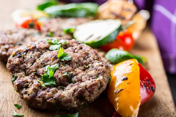 Burgers. Grill burgers. Minced burgers. Roasted burgers with grilled vegetable and herb decoration. Minced meat grilled in a hotel or restaurant