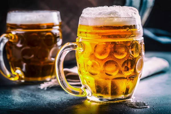 Beer. Two cold beers. Draft beer. Draft ale. Golden beer. Golden ale. Two gold beer with froth on top. Draft cold beer in glass jars in pub hotel or restaurant. Still life
