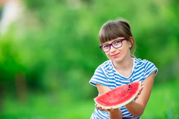 Child eating watermelon. Kids eat fruits in the garden. Pre teen girl in the garden holding a slice of water melon. happy girl kid eating watermelon. Girl kid with gasses and teeth braces