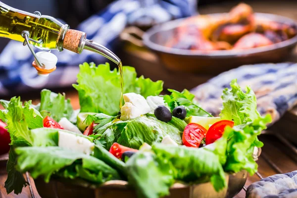 Vegetable lettuce salad. Olive oil pouring into bowl of salad. Italian Mediterranean or Greek cuisine. Vegetarian vegan food