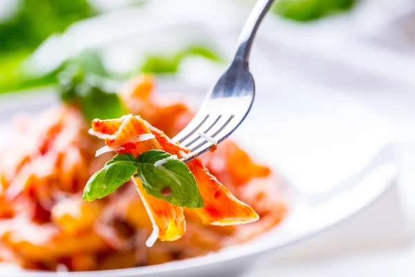 Pasta Penne with Tomato Bolognese Sauce, Parmesan Cheese and Basil on a Fork. Mediterranean food.Italian cuisine.