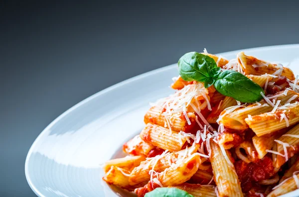 Pasta Penne with Tomato Bolognese Sauce, Parmesan Cheese and Basil Leaves. Mediterranean food.Italian cuisine