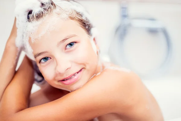 Cute young girl in shower washing hair and face with shampoo. girl with braces