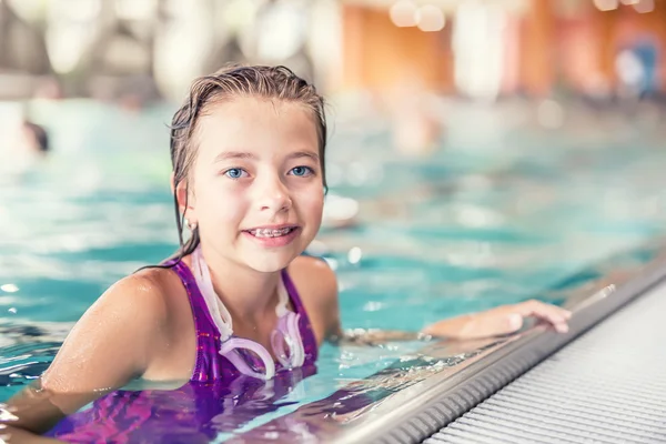 Portrait of a cute young girl with goggles in swimming pool. Swimming training
