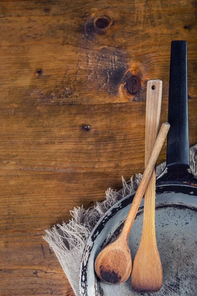 Wooden kitchen utensils on the table. Wooden spoon old pan in a retro style on wooden table.