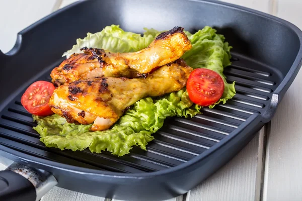 Grilling. Grilled chicken. Grilled chicken legs. Grilled chicken legs, lettuce and cherry tomatoes. Traditional cuisine.