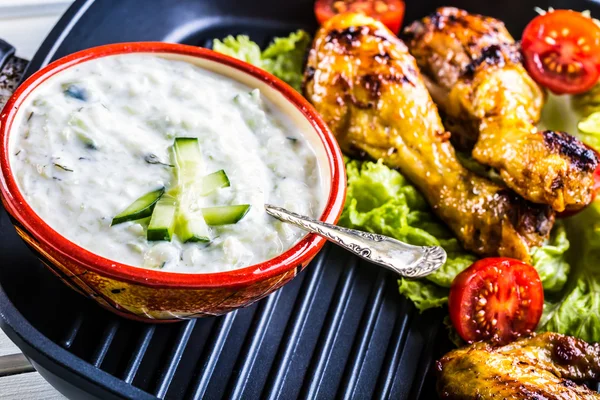 Tzatziki sauce. Tzatziki dressing. Tzatziki dressing with grilled chicken legs and fresh vegetable,lettuce leaf and cherry tomatoes. Grilled chicken legs, lettuce and tomatoes.