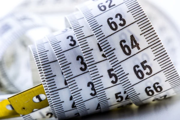 Curved measuring tape. Measuring tape of the tailor. Closeup view of white measuring tape