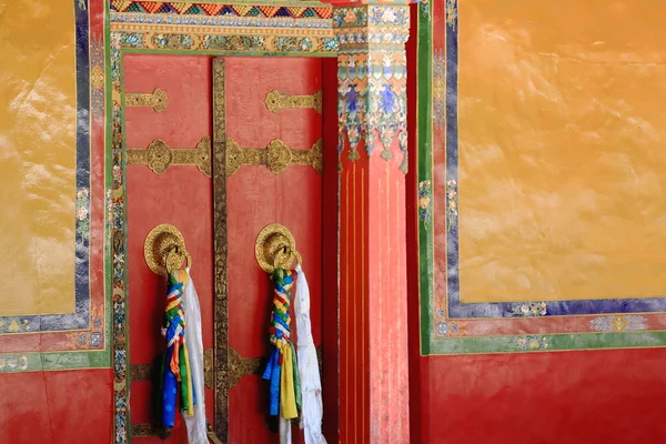 Red double door in colorist doorframe-doorknobs-batten. Drepung-Tibet. 1259