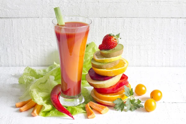 Fresh spring juice and pile of slice fruits and vegetables