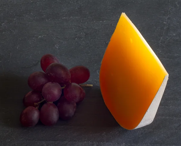 Yellow piece of cheese abstract still life with grapes