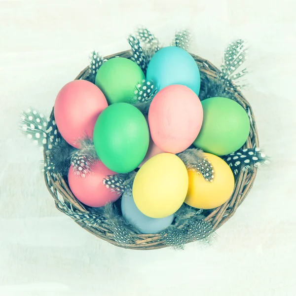 Easter eggs in basket with feather decoration vintage toned