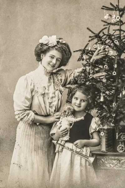 Happy mother and daughter with christmas tree and antique toys