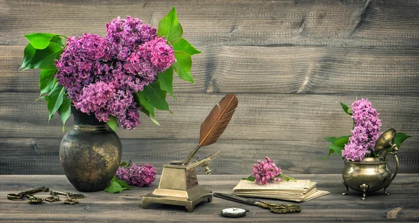 Still life with lilac flowers and antique writing tools