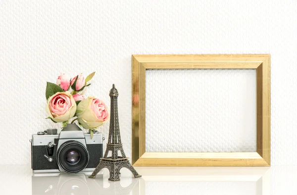 Golden picture frame, rose flowers and vintage camera. Paris tra