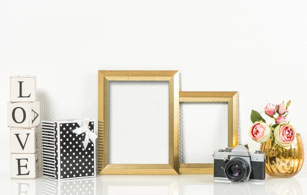 Golden picture frames, rose flowers and vintage camera. Product