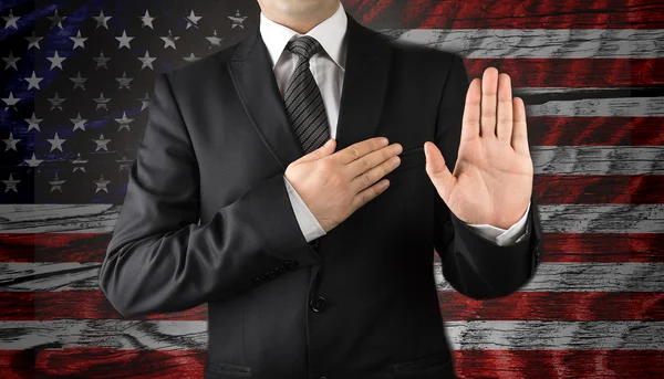 Men in suits taking oath in front of the American flag