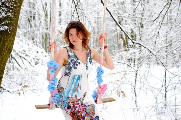 The girl on the swing in the winter forest