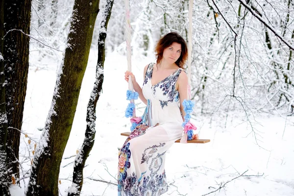 The girl on the swing in the winter forest