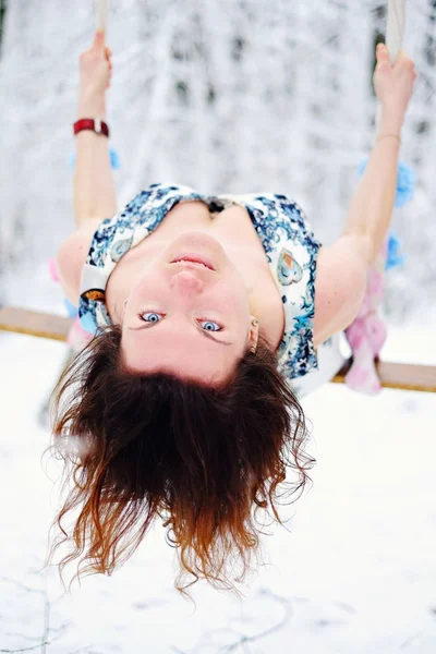 The girl on the swing in the winter forest