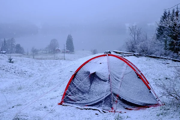 Tent in the snow at the mountain lake