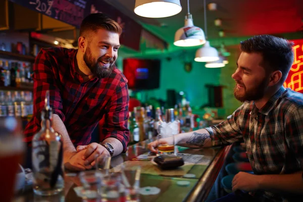 Barman and friend talking in pub