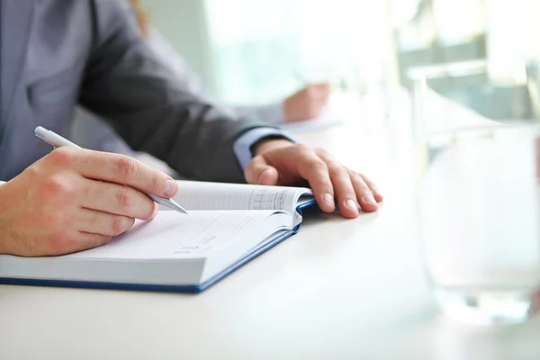 Hand of businessman writing in notebook