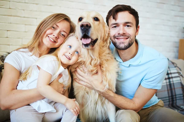 Family with dog resting on sofa
