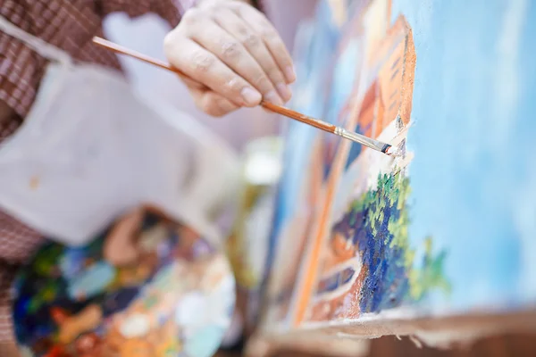 Artist with paintbrush painting on canvas