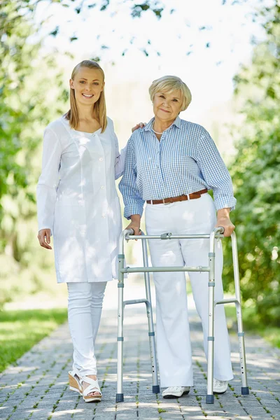 Nurse and aged patient with walking frame