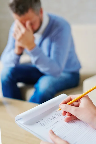 Hands of psychiatrist filling in medical document