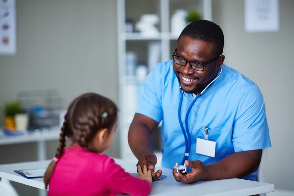 African-American clinician talking to little patient