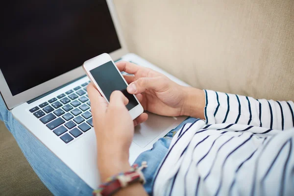 Hands with  laptop keypad and smartphone