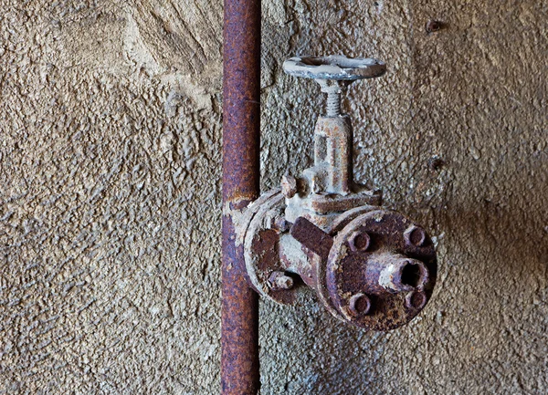 Old rusty water tap in concrete wall