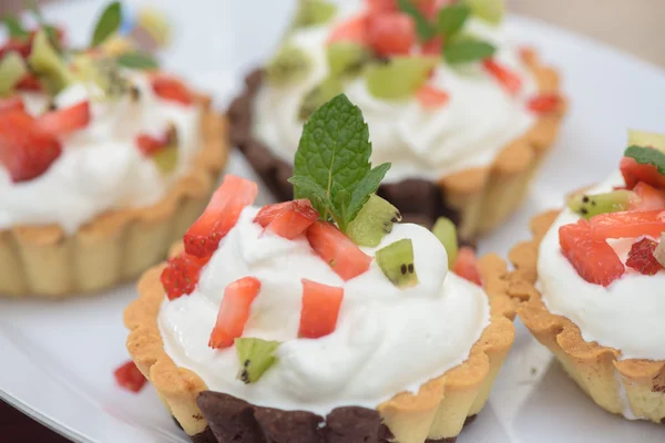 Tarts with whipped cream and strawberries and mint leaves