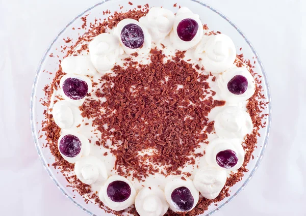 Black forest cake decorated with whipped cream and cherries.