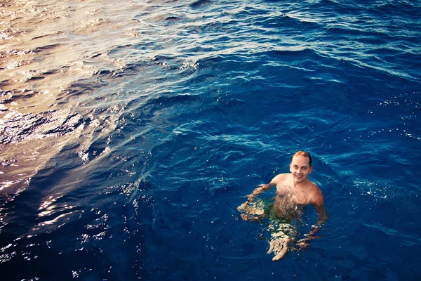 Swimming man in deep blue sea