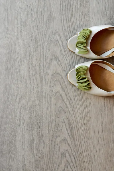 White sandals with green ribbon in with natural light