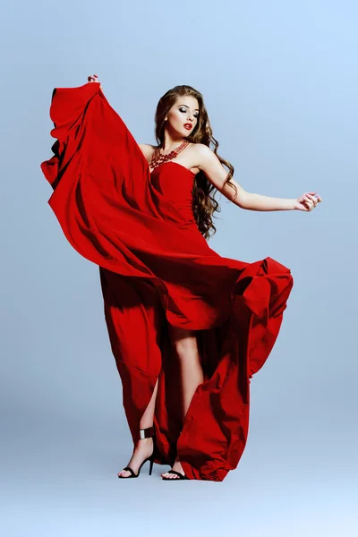 Red dress. Beautiful sexual woman in red evening dress posing in motion.