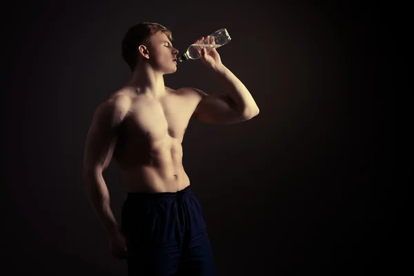 Athletic man drinking clear water after exercise.