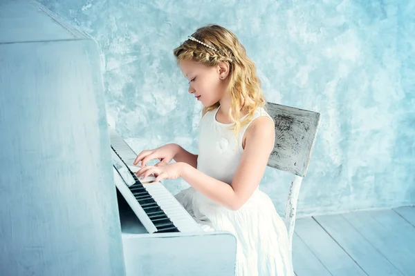 Music academy, girl in white dress playing the piano.