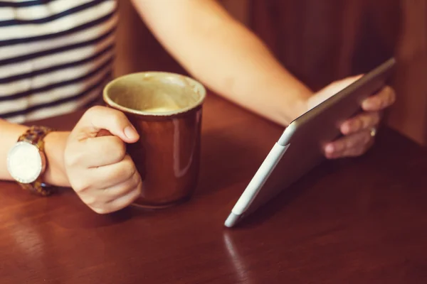 Asian woman using tablet computer in cafe drinking coffee. Focus